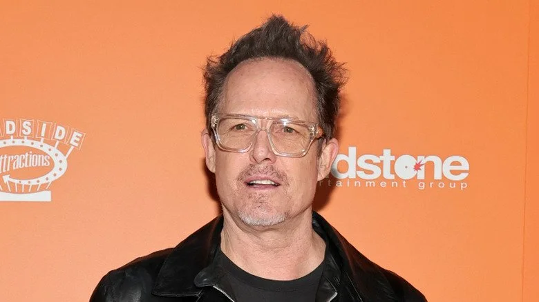 Dean Winters en lunettes, regard tourné vers l’extérieur