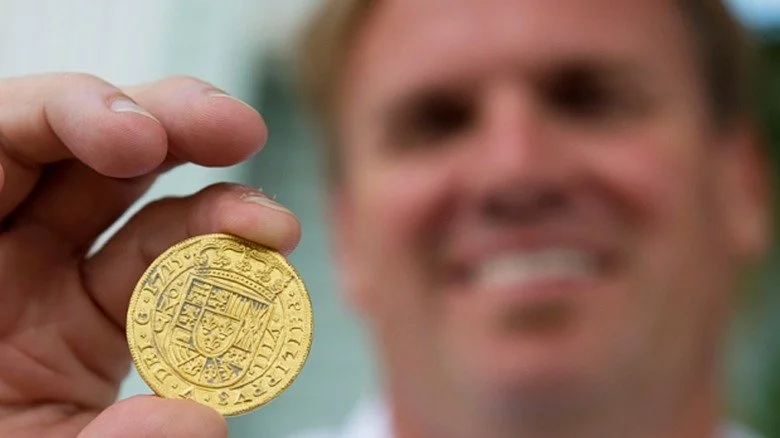 Brent Brisben tenant une pièce d’or