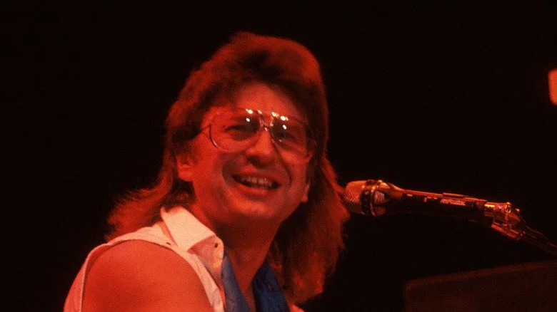 Jim Peterik assis au clavier et souriant