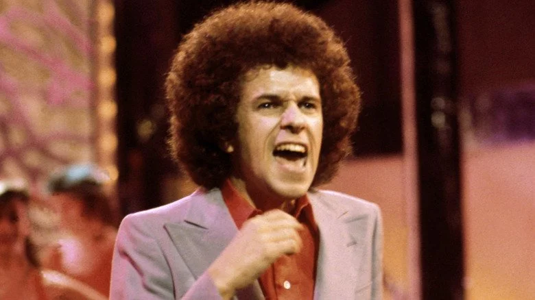 Leo Sayer chantant et dansant en costume gris