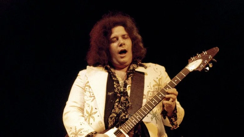 Leslie West chantant et jouant de la guitare sur scène au début des années 1970