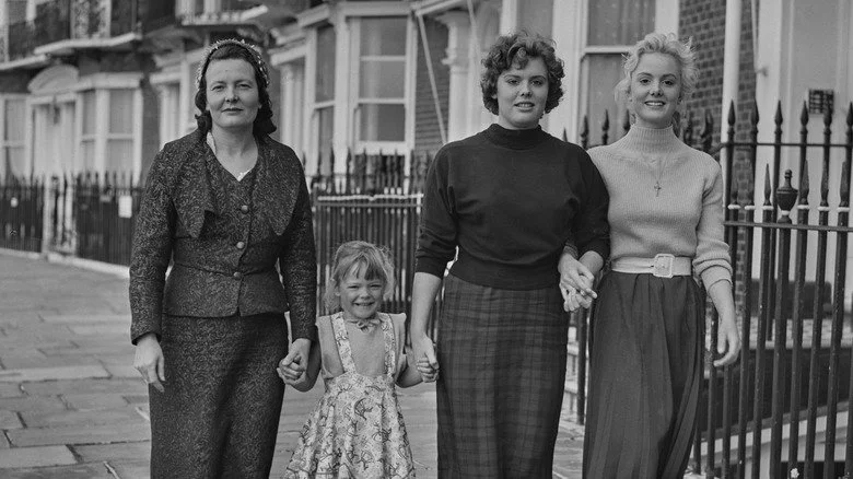 Marie Killick vêtue d'une robe chic dehors dans la rue avec ses trois filles
