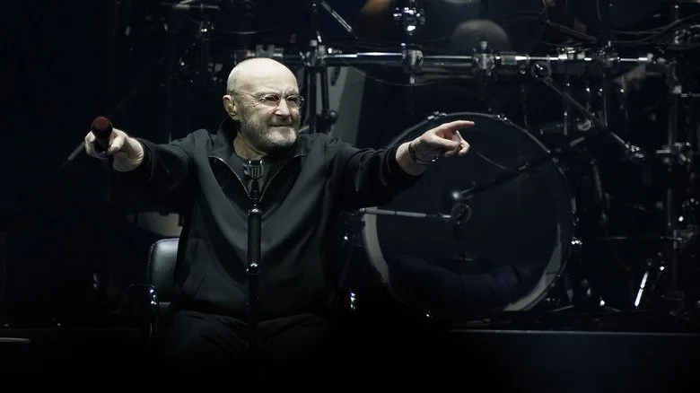 Phil Collins en représentation, assis sur scène