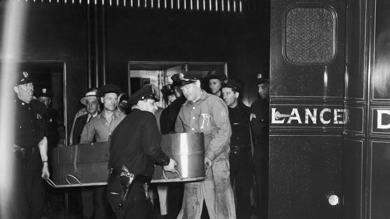 Hommes transportant un cercueil de l'Empire State Building vers une ambulance