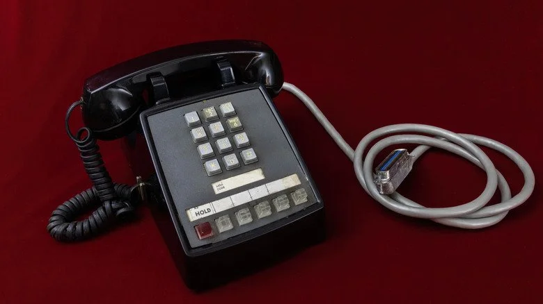 ancien téléphone noir à touches avec câble gris sur fond rouge
