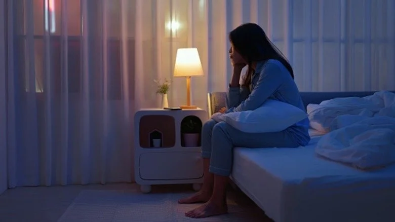 Femme assise au bord du lit, tête entre les mains