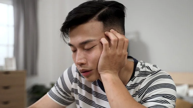 Jeune homme somnolent, la tête dans la main, gros plan