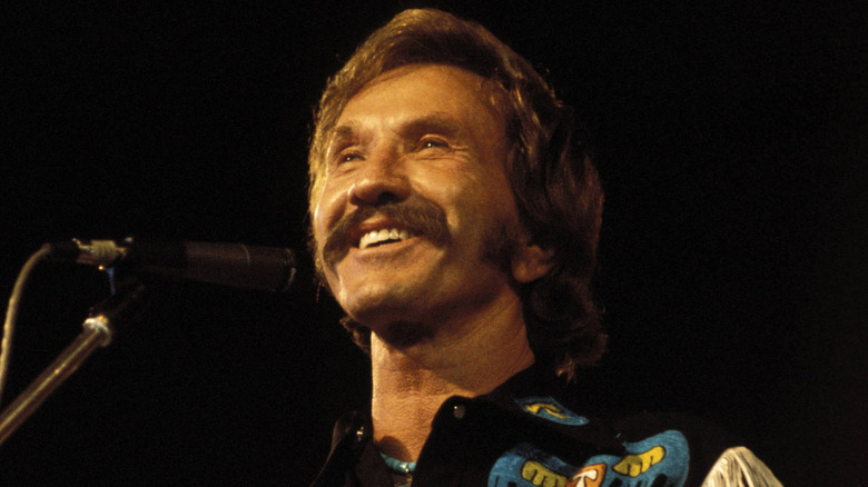 Marty Robbins souriant sur scène en tenue de cowboy