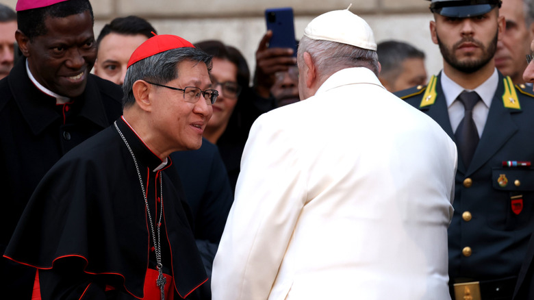 Le cardinal Tagle serrant la main du pape François en extérieur