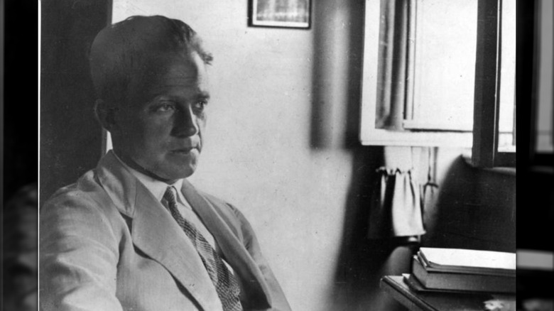 Werner Heisenberg assis à un bureau regardant dans le vide