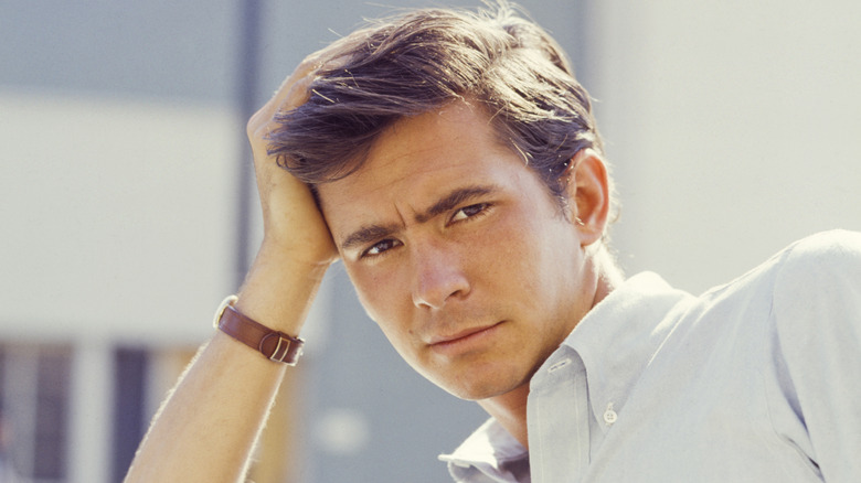Anthony Perkins appuyé sur une voiture