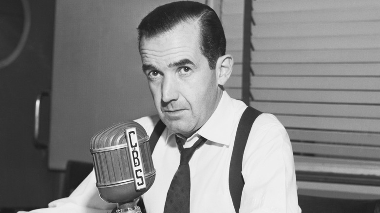 Edward R. Murrow assis près d'un micro CBS en chemise blanche et cravate desserrée