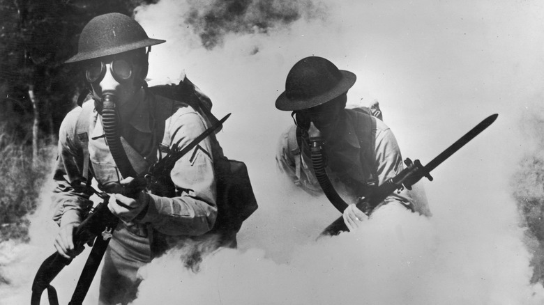 Deux soldats américains de la Première Guerre mondiale marchent dans la fumée avec des masques à gaz