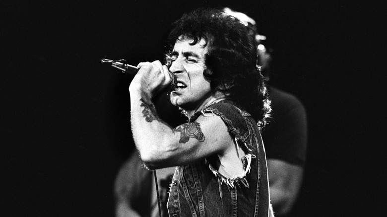 Bon Scott en veste en jean chantant sur scène