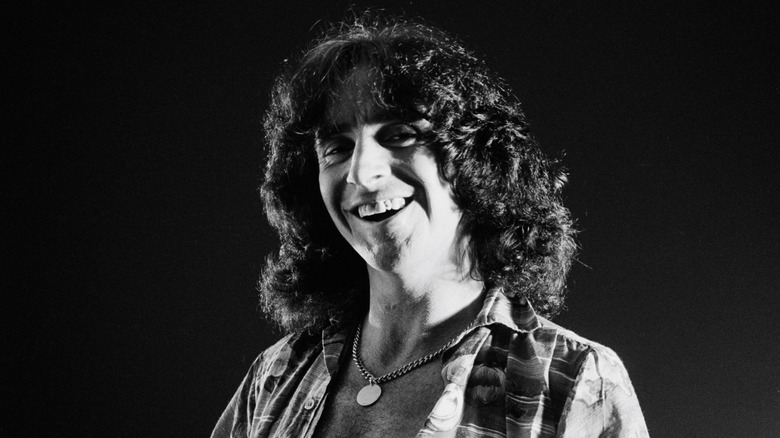 Bon Scott souriant avec un collier cheveux longs photo noir et blanc