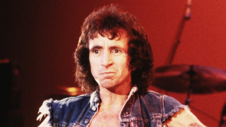 Bon Scott sur scène souriant en gilet en jean