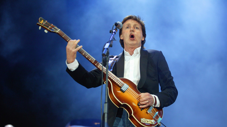 Paul McCartney sur scène en costume jouant de sa basse Hofner
