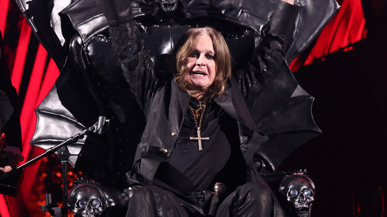 Ozzy Osbourne levant triomphalement les mains assis sur son trône