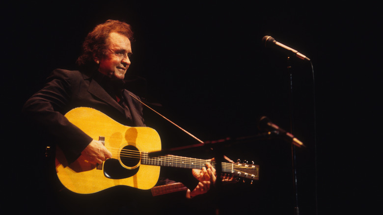 Johnny Cash jouant de la guitare acoustique devant un microphone