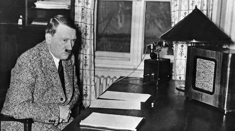 Hitler assis à son bureau écoutant une grande radio