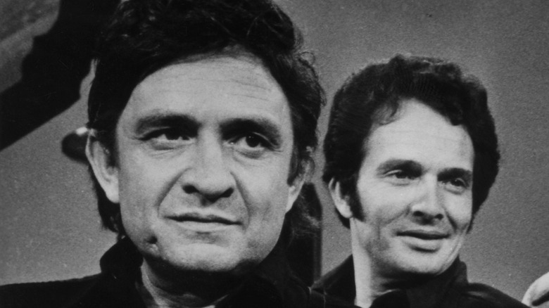 Merle Haggard debout derrière Johnny Cash