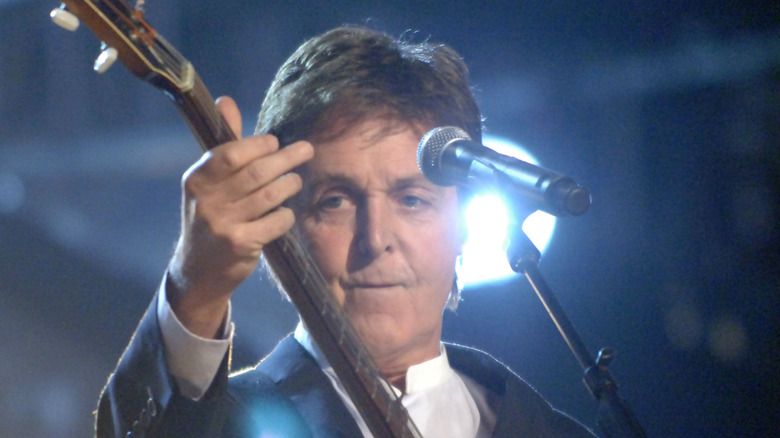 Paul McCartney sur scène en costume jouant de sa basse Hofner