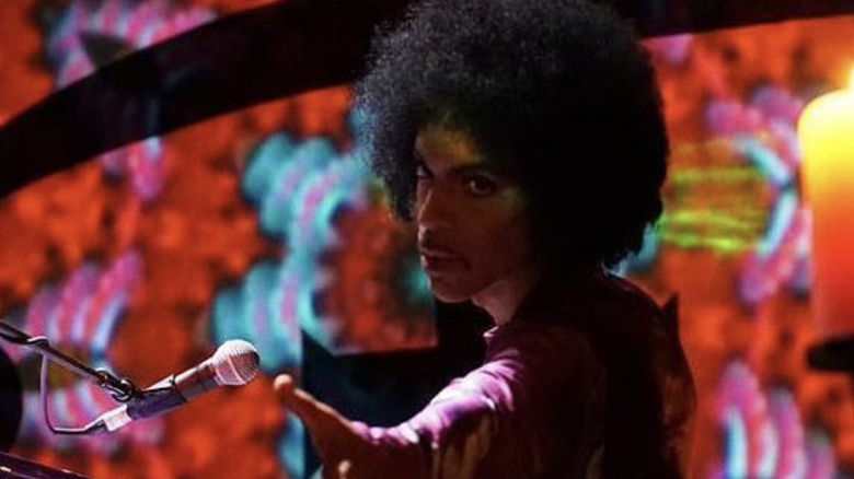 Prince tendant la main vers un membre du public depuis son piano en 2016
