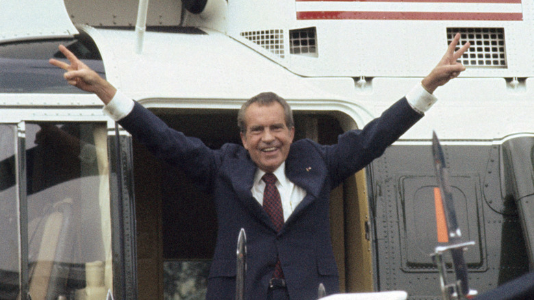 Richard Nixon montant dans un hélicoptère les bras levés