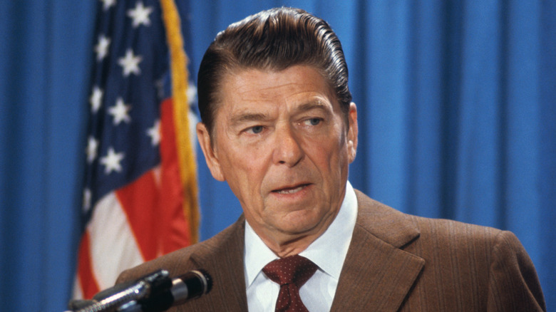 Ronald Reagan au microphone devant un drapeau