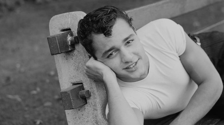 Sal Mineo souriant allongé sur un banc