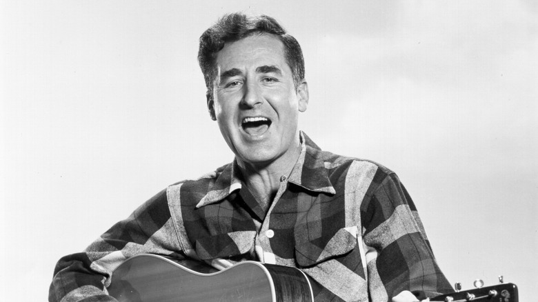 Sheb Wooley chantant et jouant de la guitare en chemise à carreaux