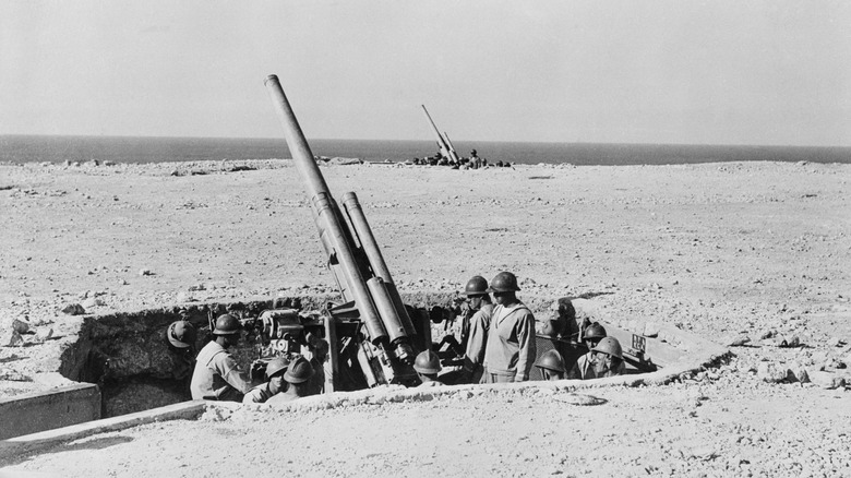 Canons et soldats italiens dans des fosses sur une plage en Libye