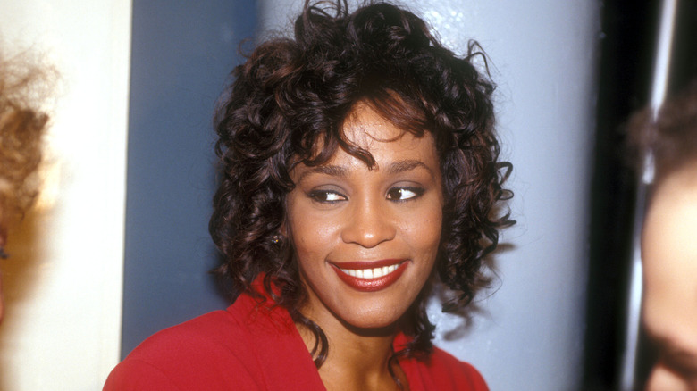 Whitney Houston souriant et regardant sur le côté