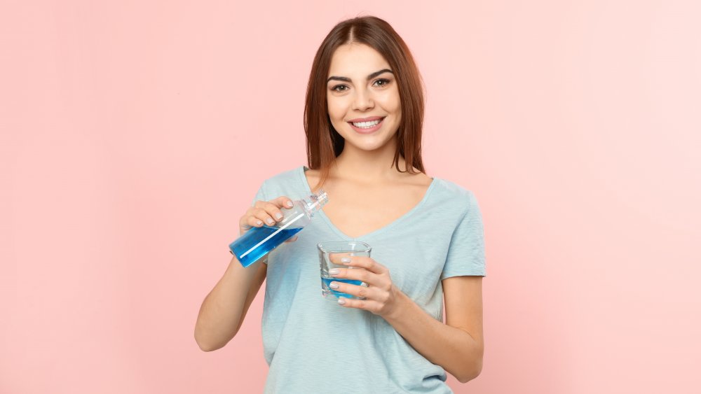 Femme tenant une bouteille de liquide bleu