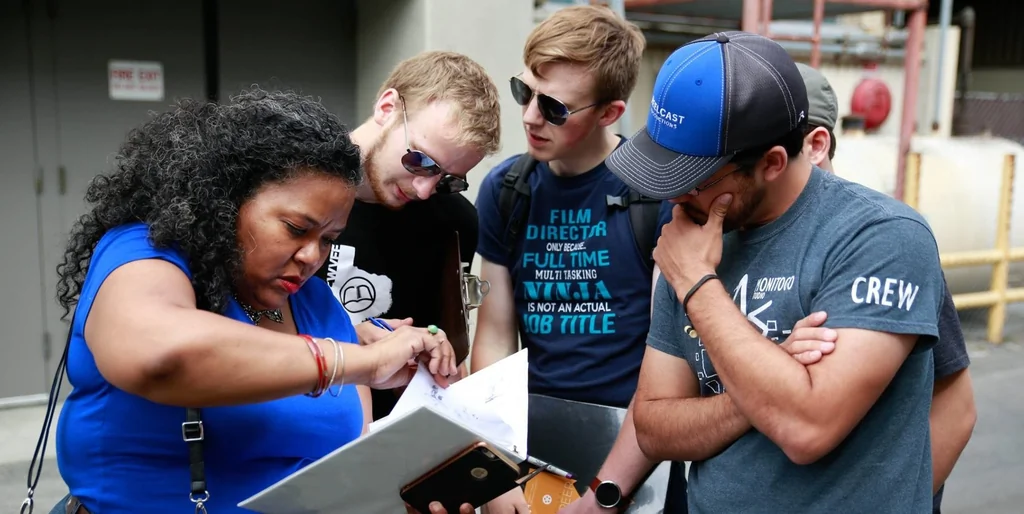 Réalisateur discutant avec son équipe technique sur un plateau de tournage extérieur