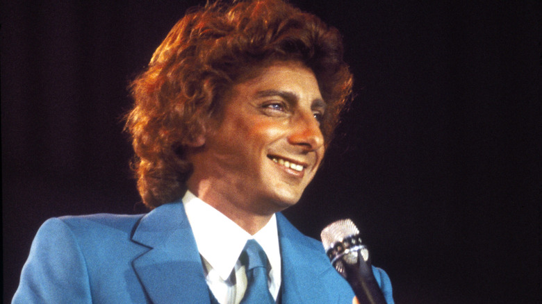 Barry Manilow tenant un microphone et portant un costume bleu