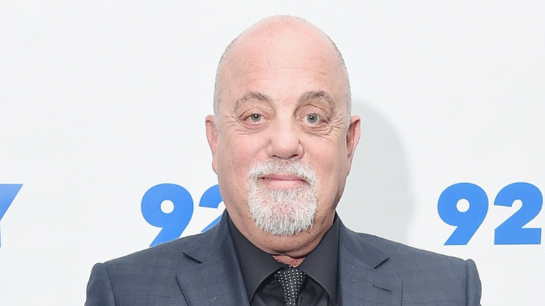 Billy Joel souriant en costume gris lors d'un événement