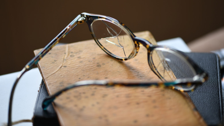 Lunettes fissurées posées sur des livres