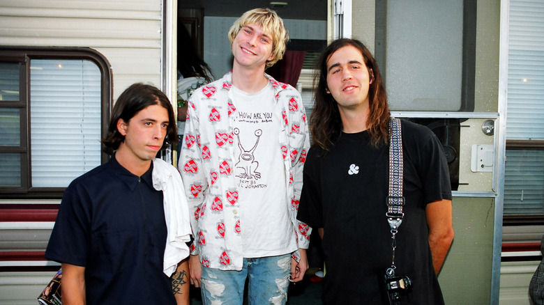 Dave Grohl, Kurt Cobain et Krist Novoselic souriant devant une caravane