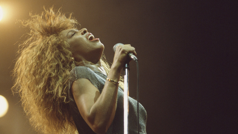 Tina Turner chantant la tête en arrière tout en tenant un microphone