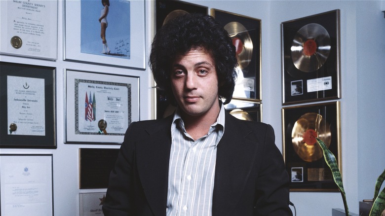Billy Joel posant devant des disques d'or