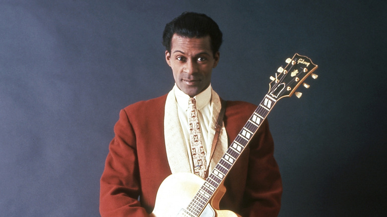 Chuck Berry en costume rouge tenant une guitare dorée