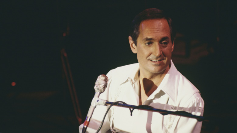 Neil Sedaka assis à son piano avec un micro