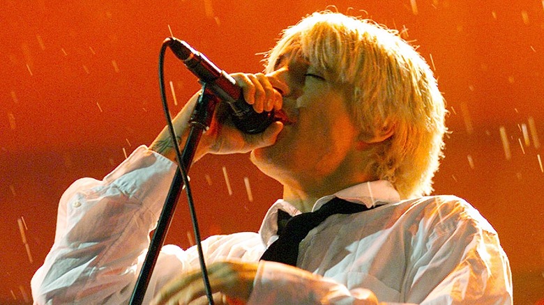 Anthony Kiedis chantant sur scène en chemise blanche