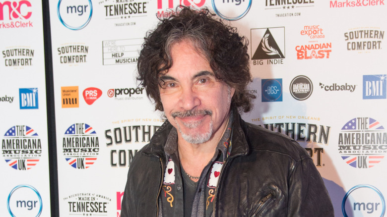 John Oates posant devant une bannière