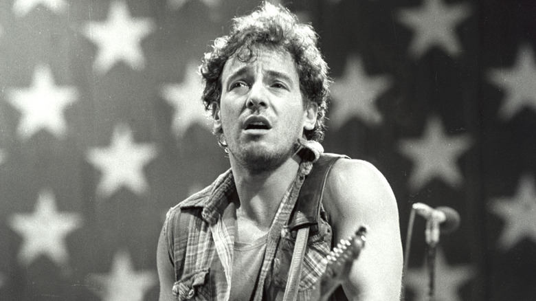 Bruce Springsteen jouant de la guitare devant un drapeau