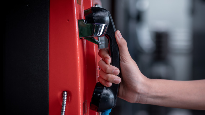 Main tenant le combiné d'un téléphone public