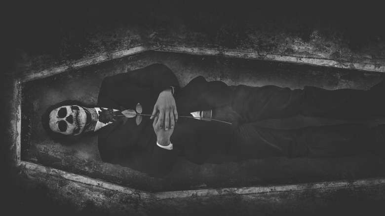 homme dans un cercueil avec visage de crâne