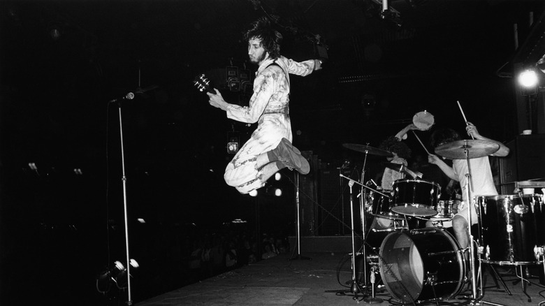 Pete Townshend de The Who sautant sur scène avec sa guitare