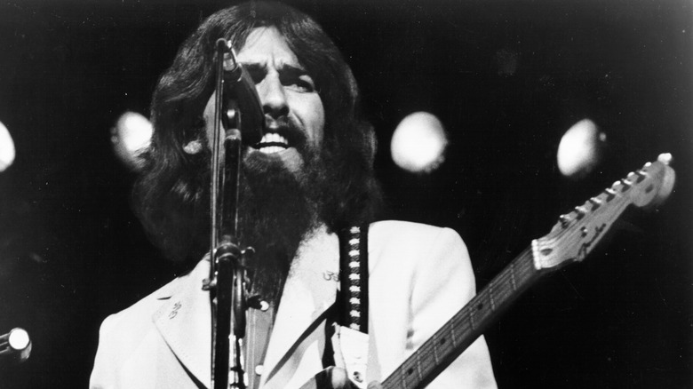 George Harrison chantant et jouant de la guitare sur scène dans les années 1970